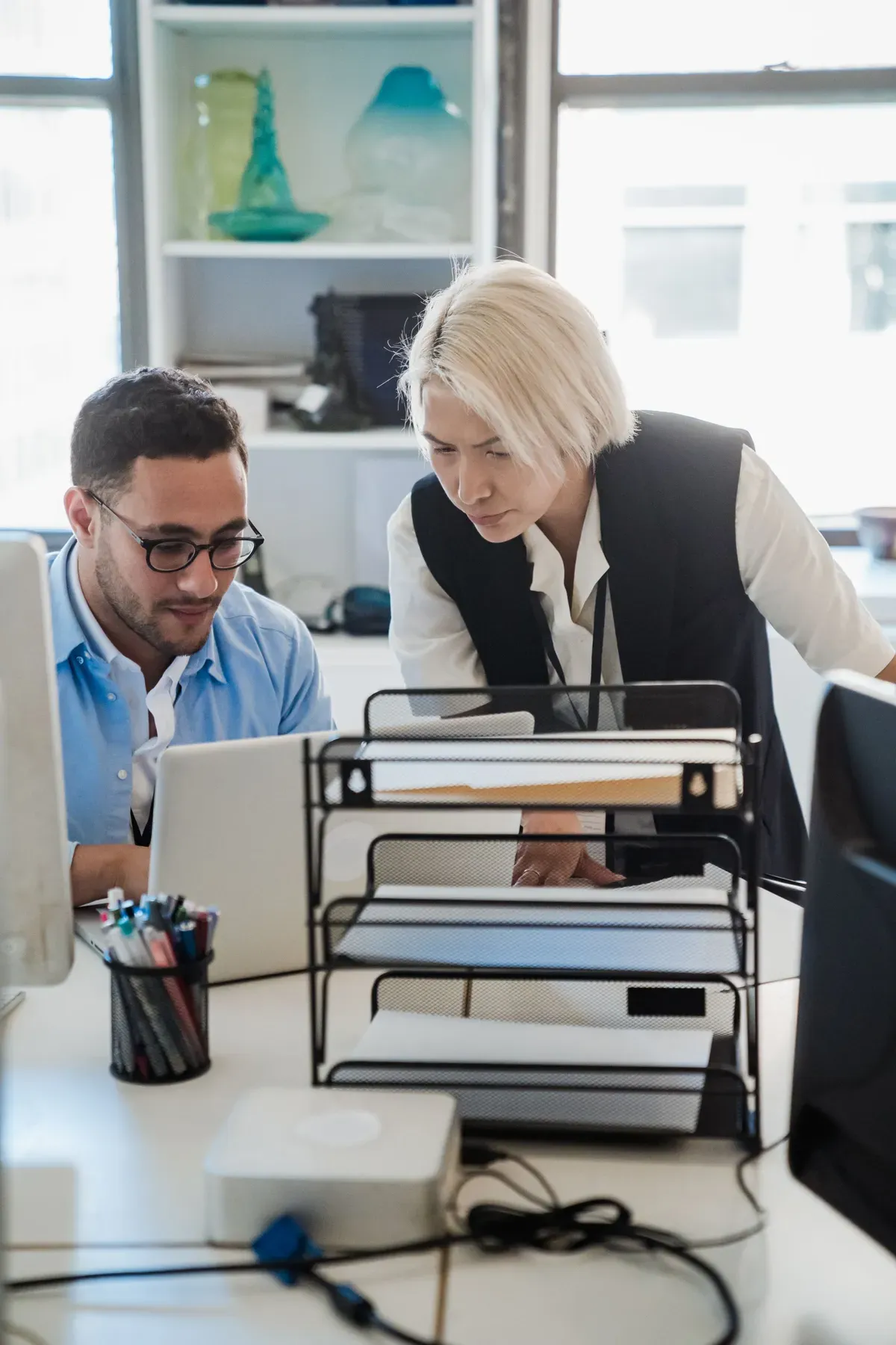 A colleague helping another at the desk